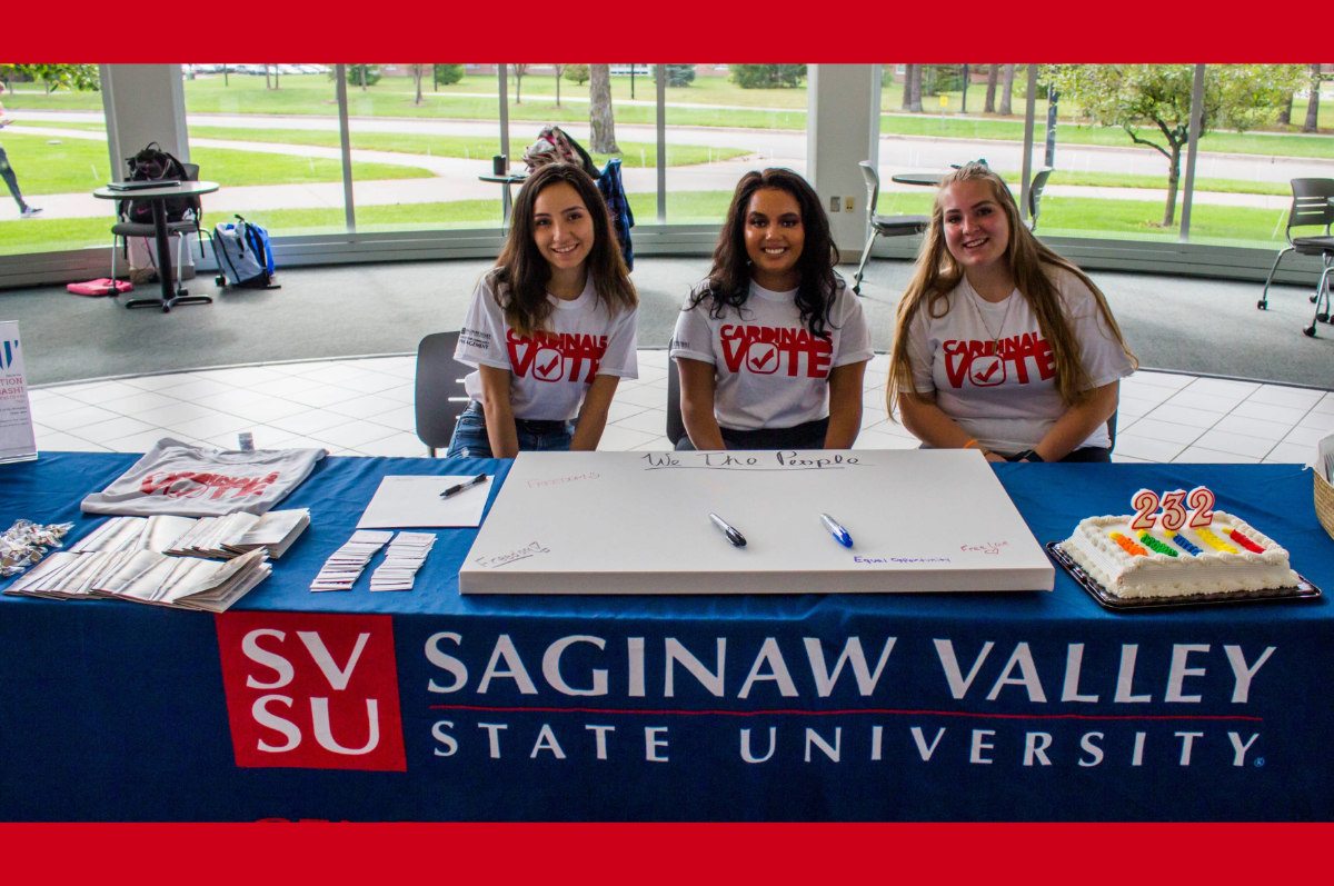 Three women sit at table draped in blue cloth